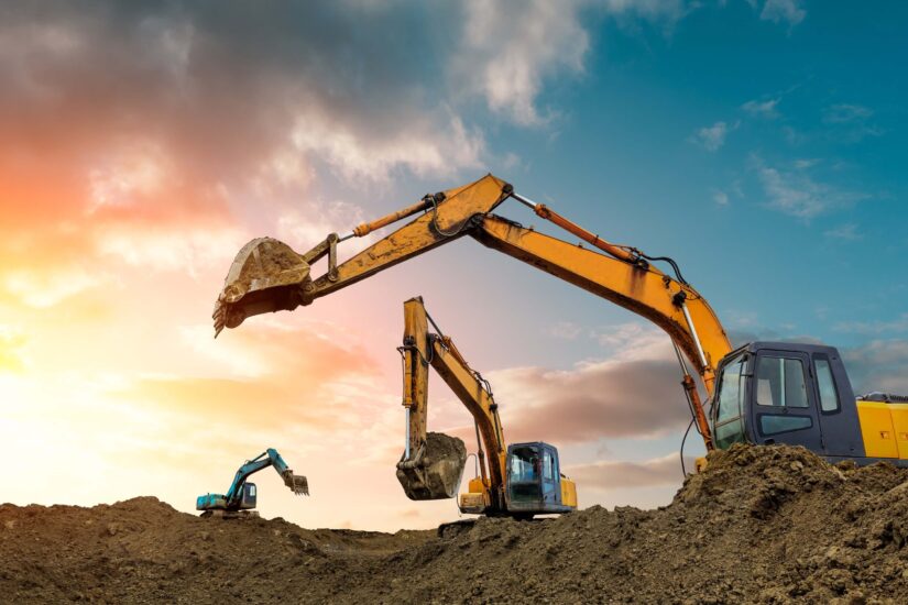 Three excavators working on construction at dusk