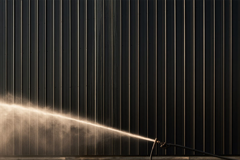 Water spots and streaking on a black metal panel being rinsed clean