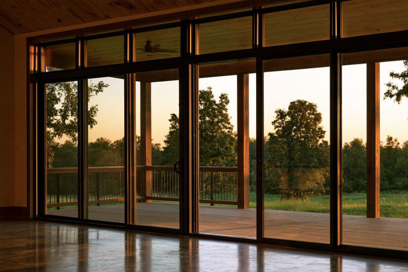 Barndominium windows and porch doors opening the living room to a wrap-around porch